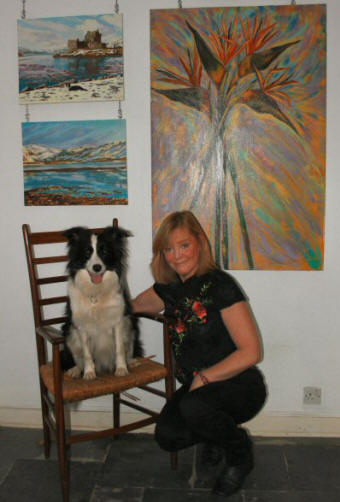 Caroline McCormack and Poppy posing in front of a selection of Caroline's oil paintings.